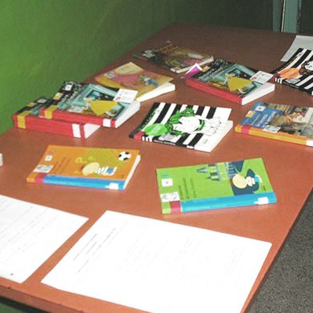 Fotografía de una mesa en una aula con libros encima.