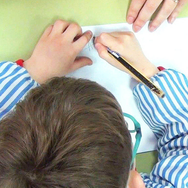 Fotografía de un niño en una aula escribiendo en una libreta.