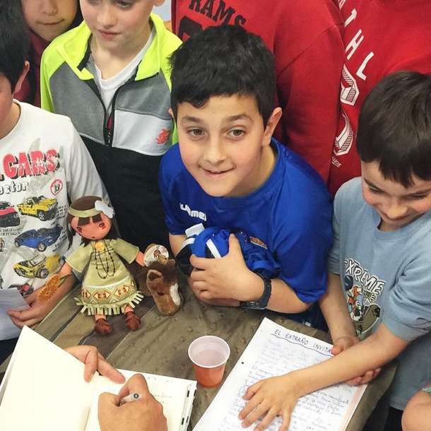 Niños en un aula escolar alrededor de una mesa con libros.