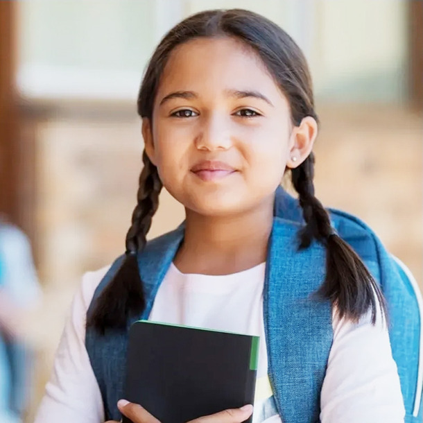 Fotografía de una niña en la escuela sosteniendo una libreta.