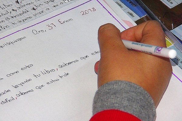 Primer plano de la mano de un niño escribiendo.