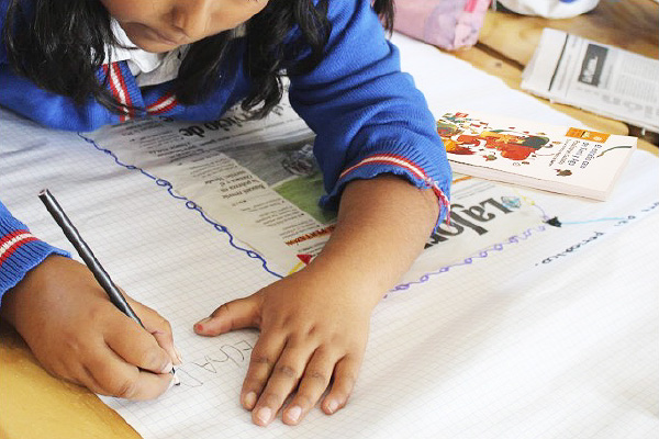 Niña de uniforme escribiendo.