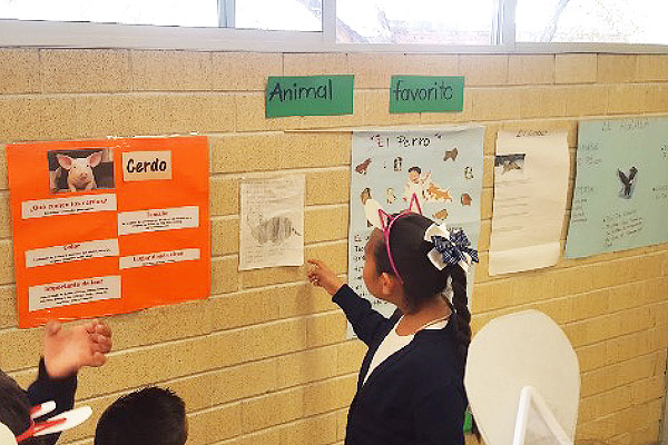 Niña escribiendo en un panel en la pared de la escuela.